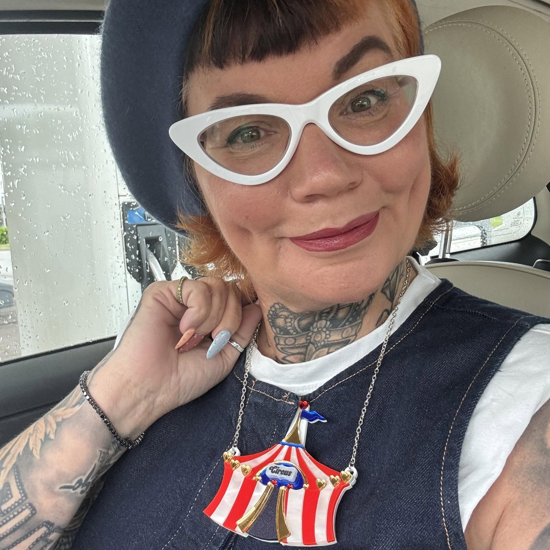 Gilly Gilmour smiling in white cat-eye glasses and a dark beret